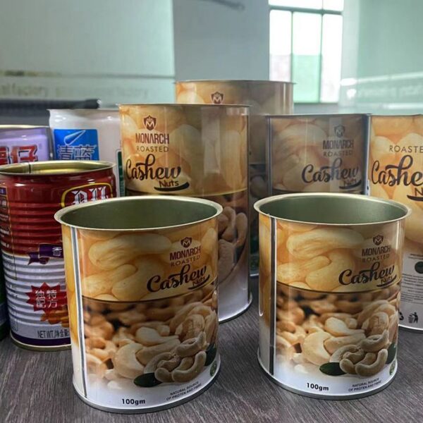 Several metal tins and boxes of Monarch roasted cashew nuts on a countertop shelf.