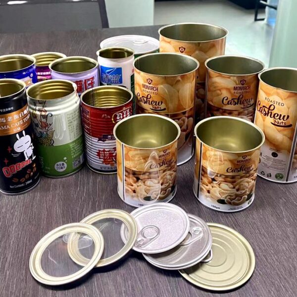 Assortment of cashew-nut tins on a table, mostly Monarch Roasted Cashews, with several open lids and pull rings nearby.